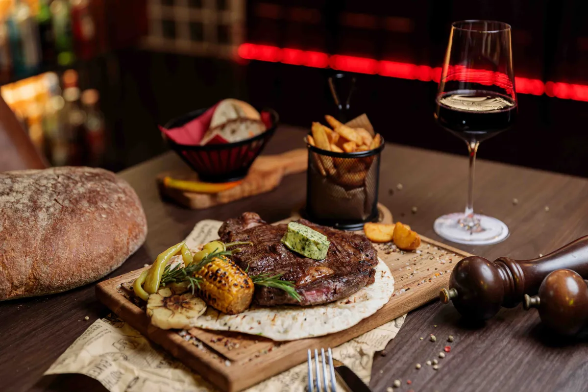 Steak mit Beilagen und Rotwein auf einem Tisch bei Fass & Flamme
