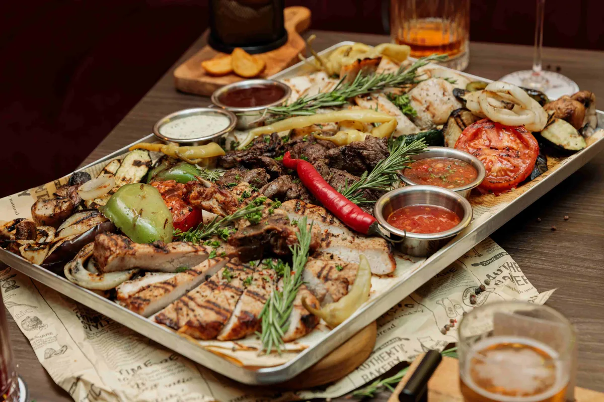 Grillplatte mit Fleisch, Gemüse und Saucen für die Runde
